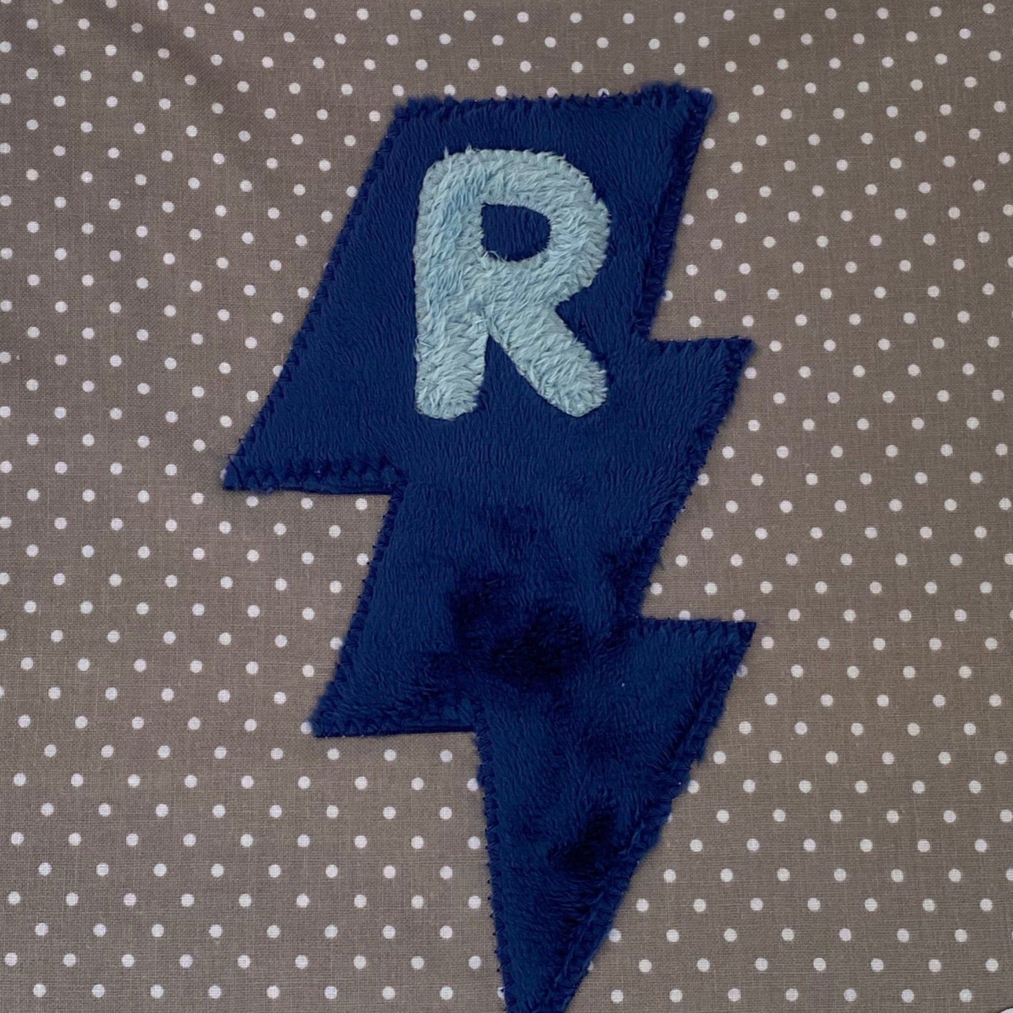 Tiny dot bib with light blue initial and navy blue lightning bolt